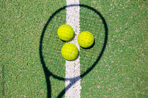 Tennis balls and shadow from racket on a green tennis hard court