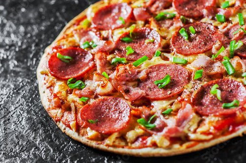 Pepperoni Pizza with Mozzarella cheese  salami  bacon  Tomato sauce  pepper  Spices and Fresh green onion. Italian pizza on black background