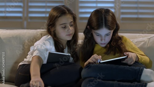 Children playing games on their digital tablets at home