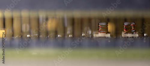 Close up (Macro) of Printed Circuit Board PCB embedded components (inductors, resistors, capacitors, diodes, microchips, transistor) with short depth of view. 