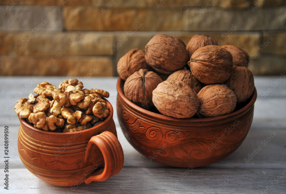 Walnut peeled and inshell in pottery on a white wooden table. Walnut peeled and inshell in pottery on a white wooden table.