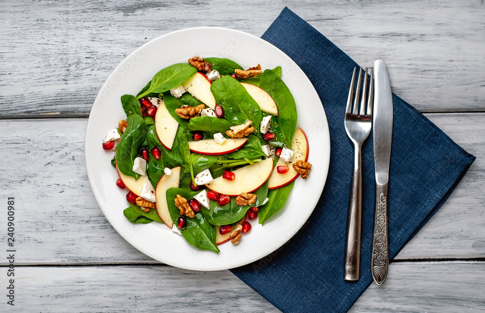 spinach salad, apple, pomegranate, cheese, walnut salad on wooden steel spinach salad, apple, pomegranate, cheese, walnut salad on wooden steel