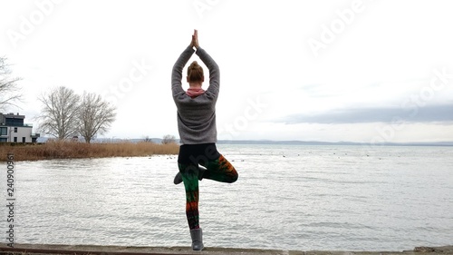 young woman practicing yoga at the lake