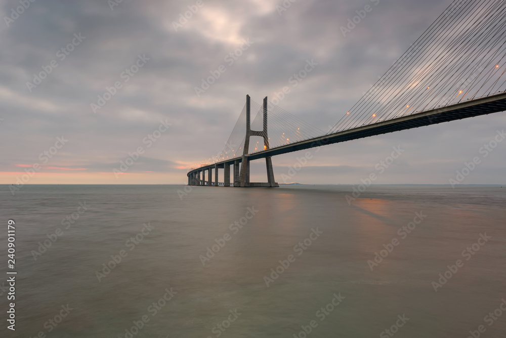 Fototapeta premium Urban landscape at sunrise. Lisbon is an amazing tourist destination. The Vasco da Gama Bridge is a beautiful landmark, and one of the longest bridges in the world. Portugal in a dawn light.