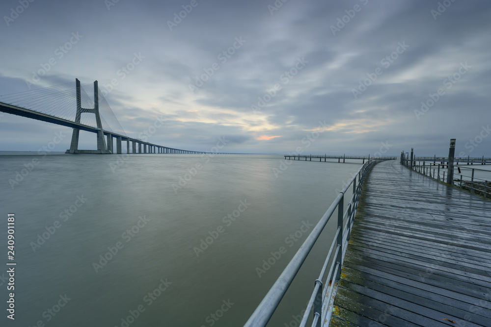 Fototapeta premium Urban landscape at sunrise. Lisbon is an amazing tourist destination. The Vasco da Gama Bridge is a beautiful landmark, and one of the longest bridges in the world. Portugal in a dawn light.