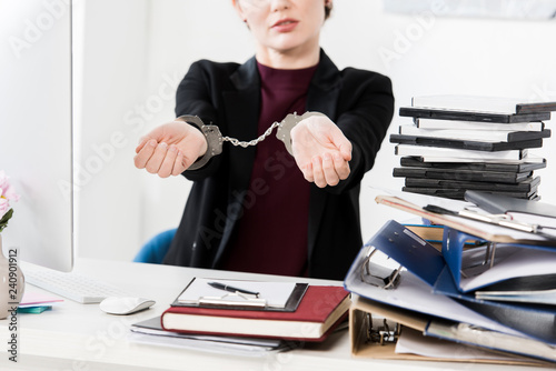 cropped image of businesswoman showing hands with handcuffs in office