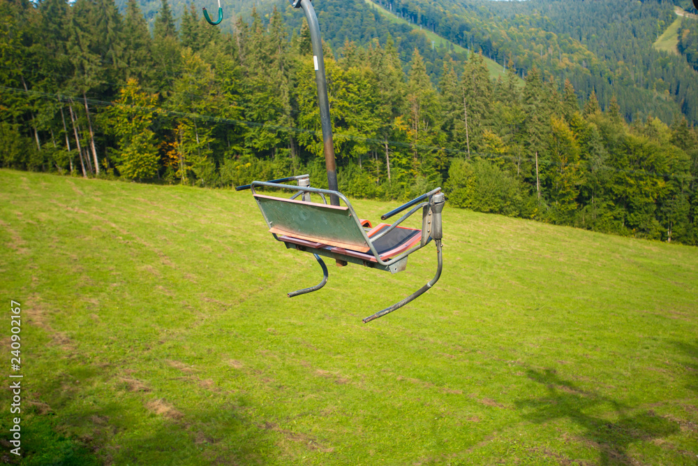 Emtpy chairlift in ski resort. Mountains and hills with in Summer with green trees