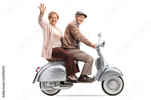 Senior couple riding a vintage scooter and waving