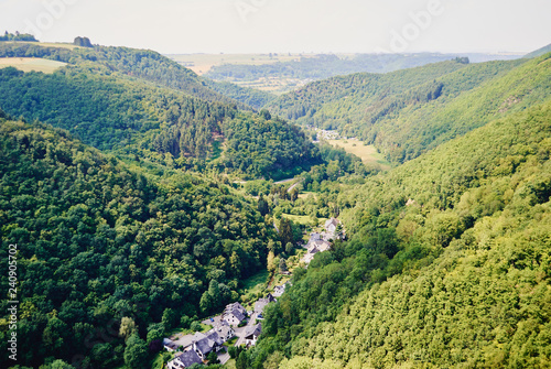 Top view of the small village surrounded by green hills covered with forest