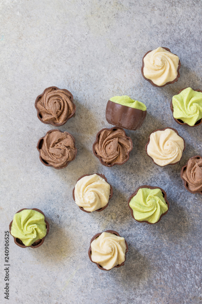 Yummy Assortment chocolate candies. Chocolate with vanilla, chocolate and pistachio cream on marble background. Top view flat lay background.