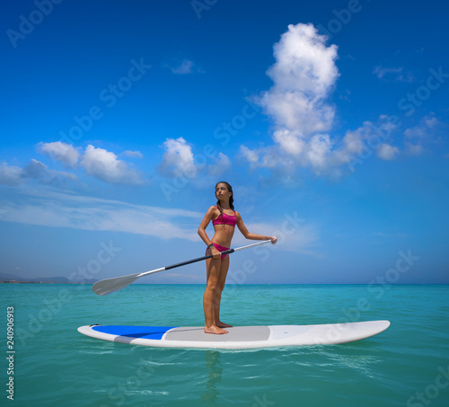 Girl standing on paddle surf board SUP