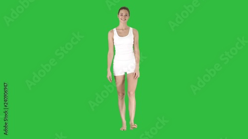 Young sexy woman walking and smiling dressed in white shorts and t-shirt on a Green Screen, Chroma Key.