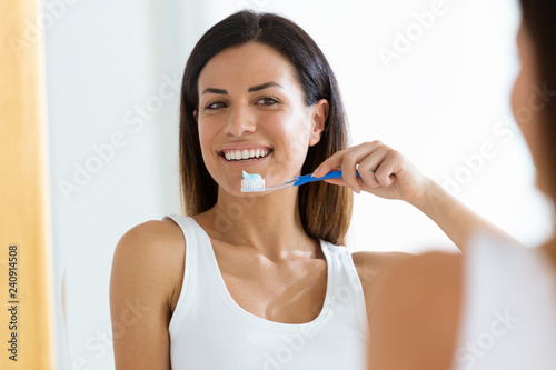 Pretty young woman brushing her teeth in the bathroom at home.
