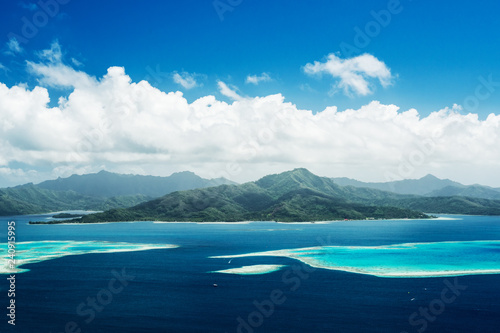 Scenic aerial view on lagoon with blue and turquoise water, barrier reef, blue sky and white clouds of Raiatea island in French Polynesia photo