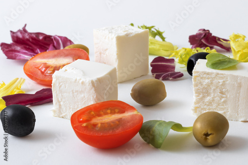 Greek salad, white Greek cheese, green and black olives, lettuce leaves, halfs of cherry tomato. White background. variations of salad leaves and feta myzithra cheese. photo