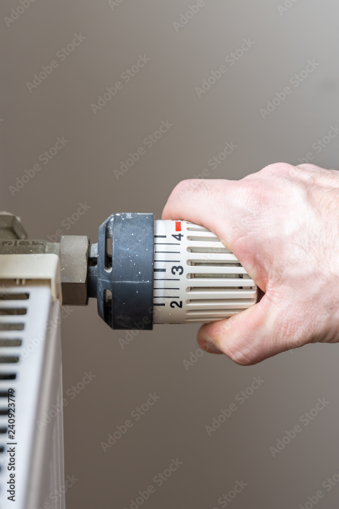 Male hand changing temperature on radiator. Male hand changing temperature on radiator.