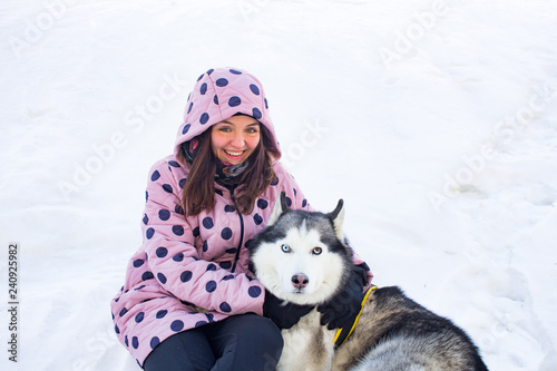 young woman with husky dok sitting on the snow