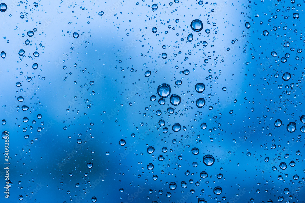 Water drops on glass window blue background after the rain in the autumn fall