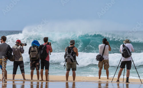 People admiring the big waves and photographers taking pictures of the big waves of Pipeline beach in Hawaii during the winter season.