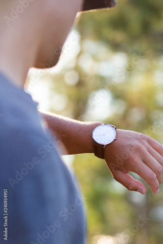 A man checks his wristwatch while on a sunny vacation to see if he needs to leave