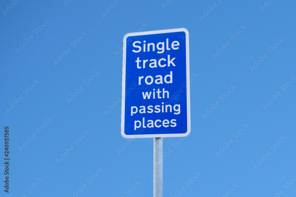 Single track road with passing places sign post against blue sky Single track road with passing places sign post against blue sky