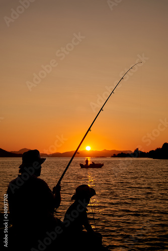 Seaside or beach fishing man and kid at sunset
