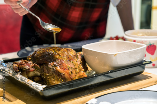 A roast leg of lamb on baking tray on christmas table