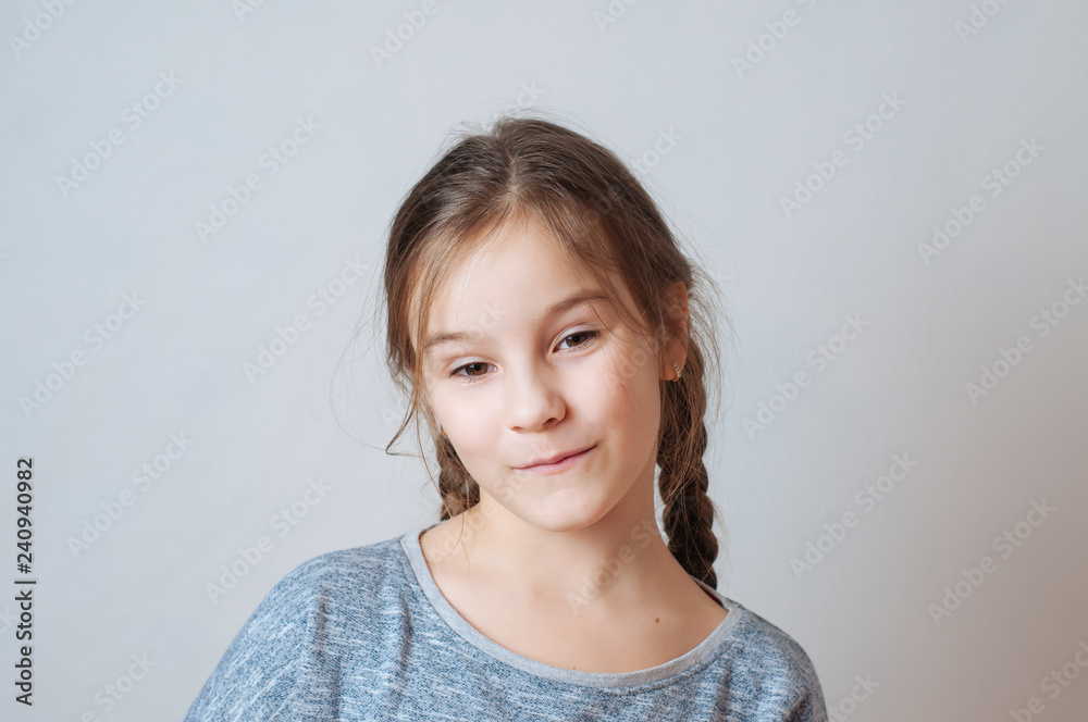 Little girl with a sly look and pigtails on a neutral background Little girl with a sly look and pigtails on a neutral background