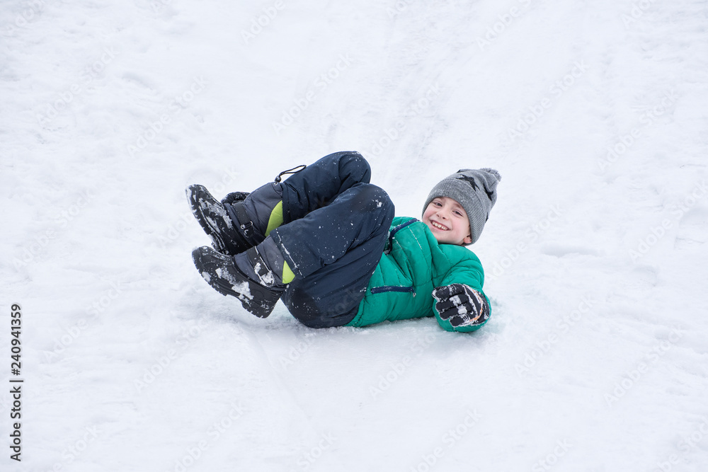Boy falls rolling down a snowy hill. Winter games