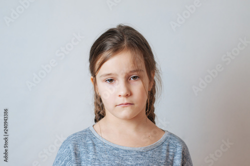 Sad little girl with pigtails portrait on a neutral background