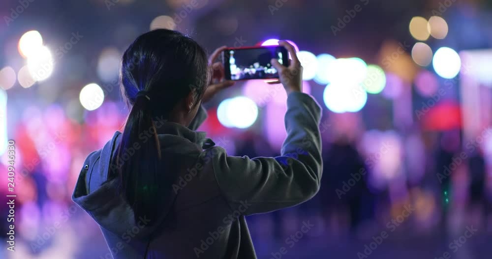 Woman take photo on mobile phone in the street at night Woman take photo on mobile phone in the street at night