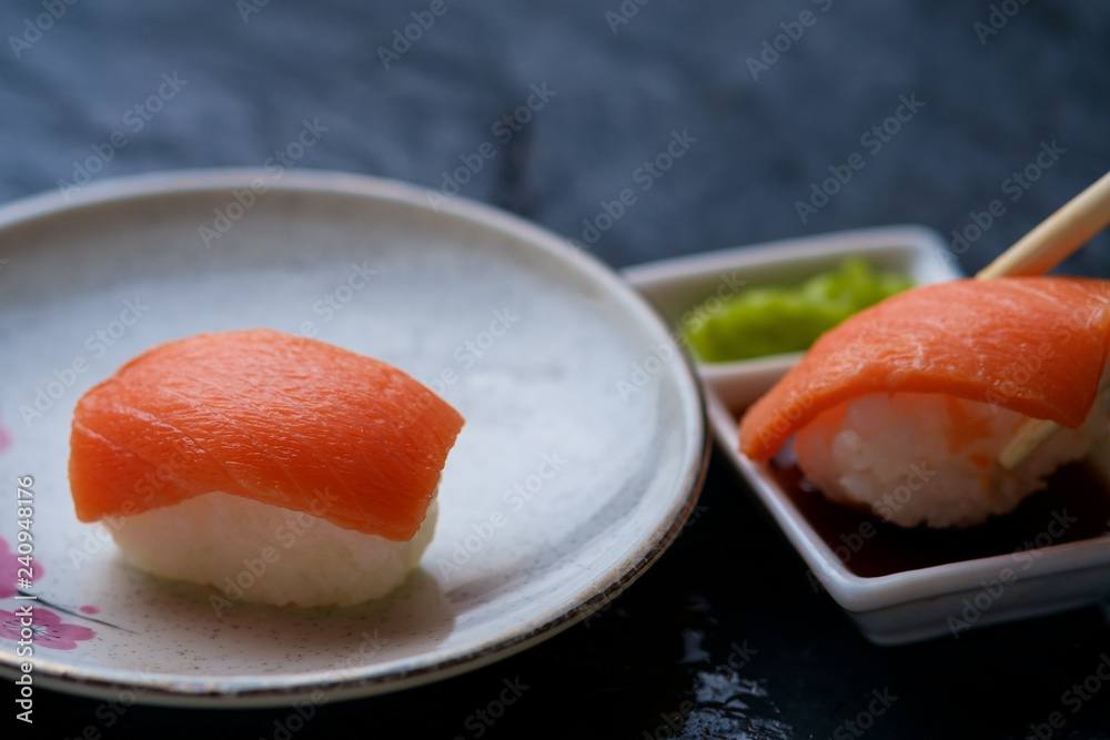 Dipping a salmon sushi in the soy sauce Dipping a salmon sushi in the soy sauce