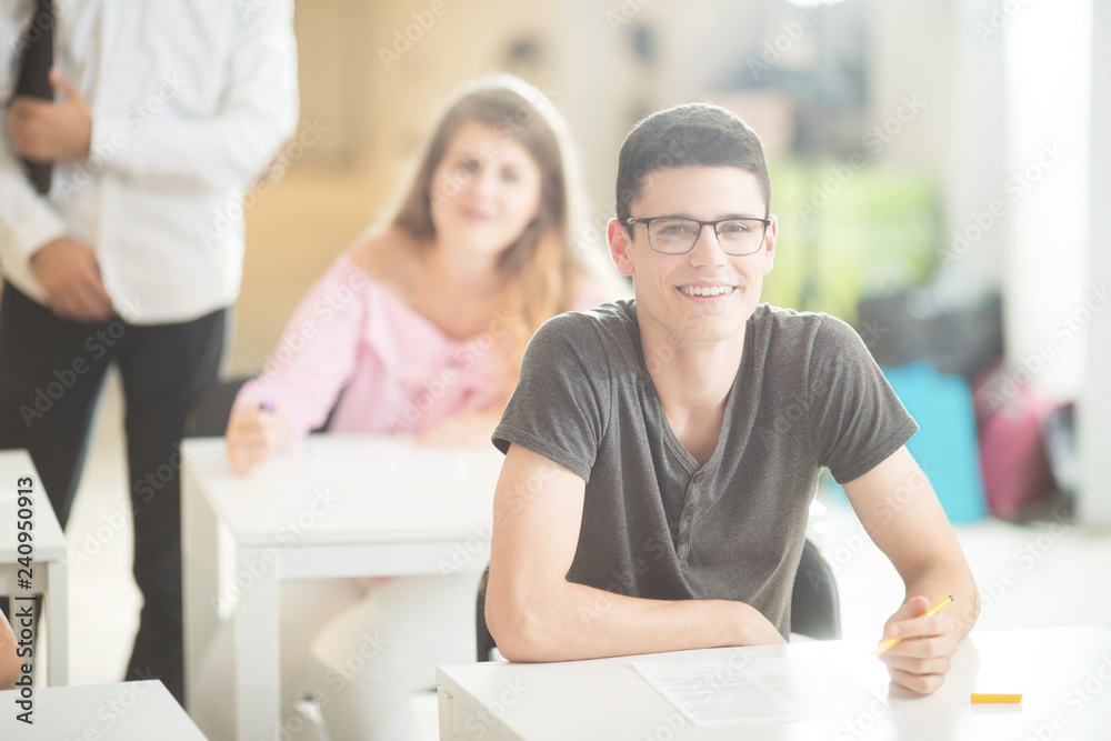 Young student smiling and sitting with other students in classroom