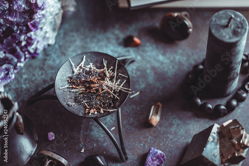 Burning herbs on a witch's altar for a magical ritual among crystals and black candles.