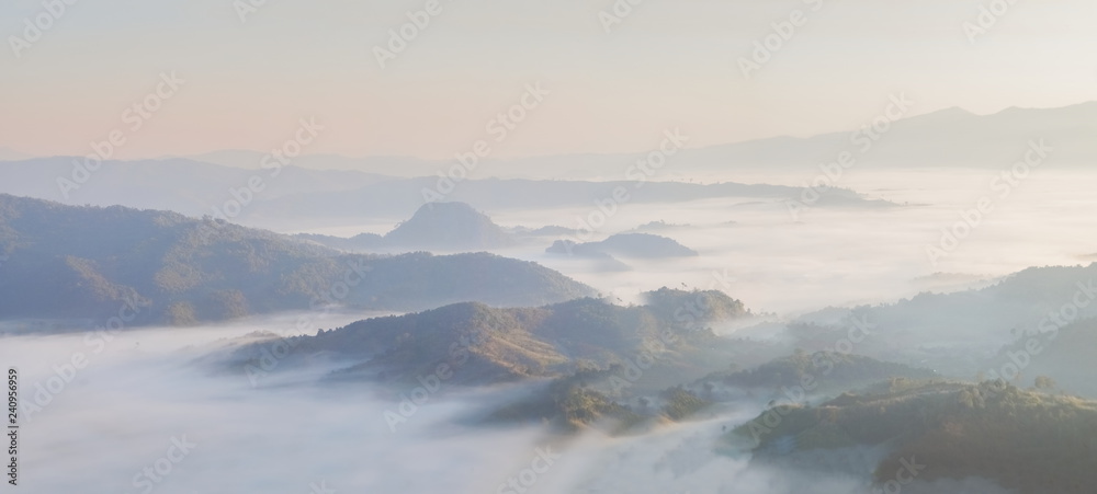 Fototapeta premium skyline mountain view panorama misty morning, view of the hill and green forest around with the ocean of mist with blue sky background, sunrise at Tham Sakoen View Point, Nan, Thailand.