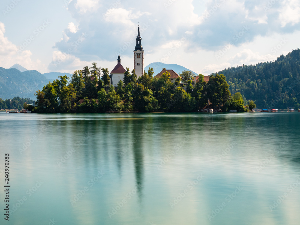 Long exposure of Lake Bled Slovenia, early morning, cloudy day, reflections in the water, side view of the island in the foreground