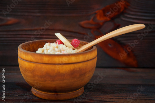 Tasty oatmeal with banana and raspberries in a wooden bowl photo