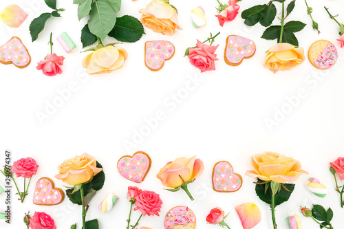 Fototapeta Naklejka Na Ścianę i Meble -  Frame with roses flowers and sweet cookies on white background. Flat lay. Valentines day