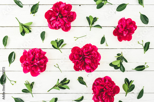 Floral pattern composition made of red peony flowers and leaves on white rustic background. Flat lay, top view.