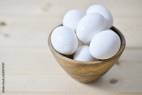 white eggs on wooden plate on wooden background , copy space 