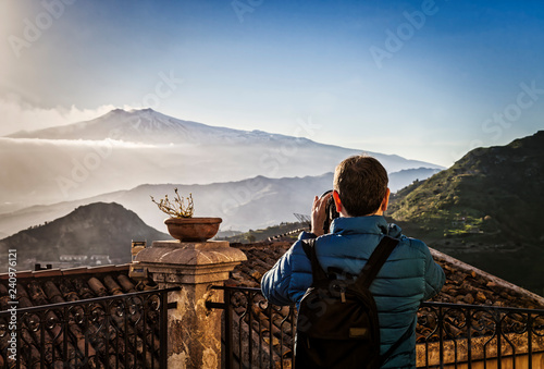 Woman photographing etna volcano during eruption