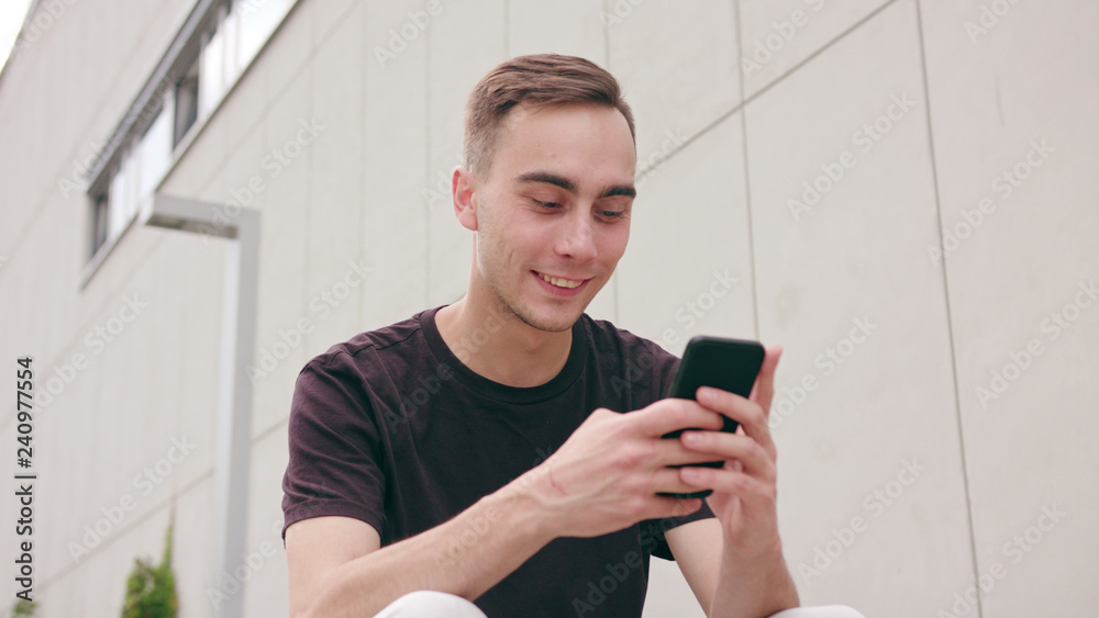 A young man using a phone in the city street. Close-up shot. Soft focus A young man using a phone in the city street. Close-up shot. Soft focus