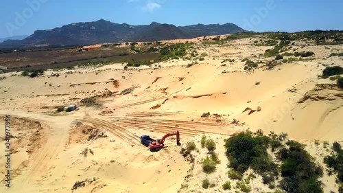 aerial picture deep sand pit with truck near operating excavator and hills on horizon under blue sky
