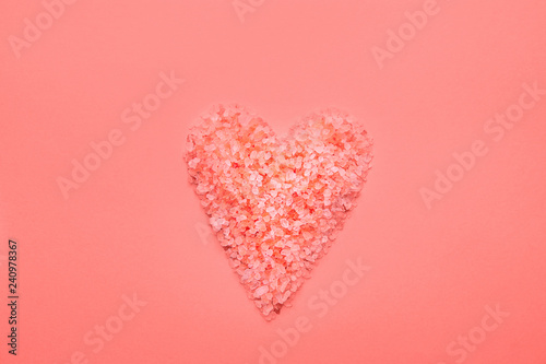 Heart symbol in trendy living coral color made from pink Himalaya salt crystals on monochrome background. Valentine Mother's Day Romantic Love Charity Concept. Greeting card banner poster template