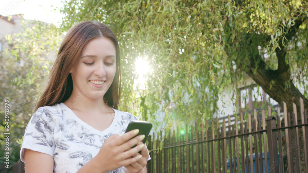 An attractive young lady using a phone in town while walking. Close-up dolly shot. Soft focus An attractive young lady using a phone in town while walking. Close-up dolly shot. Soft focus