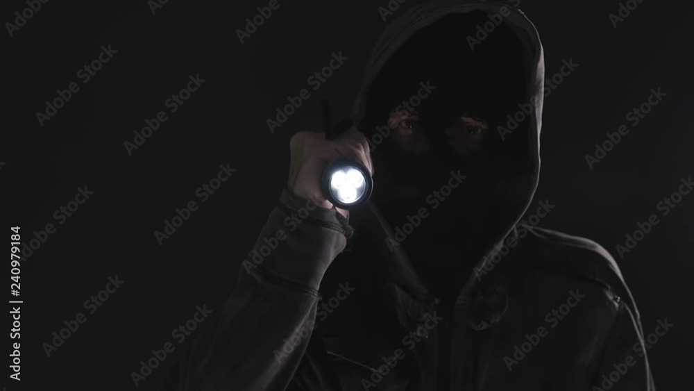 Home invasion, burglar with flashlight torch invading home at night, low key selective focus slow motion, 