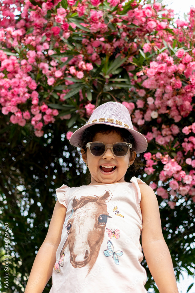 Beautiful girl with glasses and hat in front of flowers