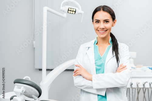 Φωτογραφία beautiful dentist standing with crossed arms in dental clinic