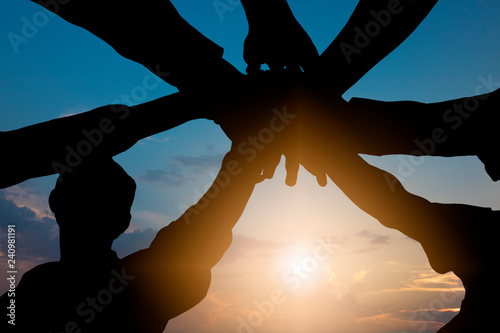 Bild auf Leinwand unity and teamwork concept, silhouette of group people putting hand together