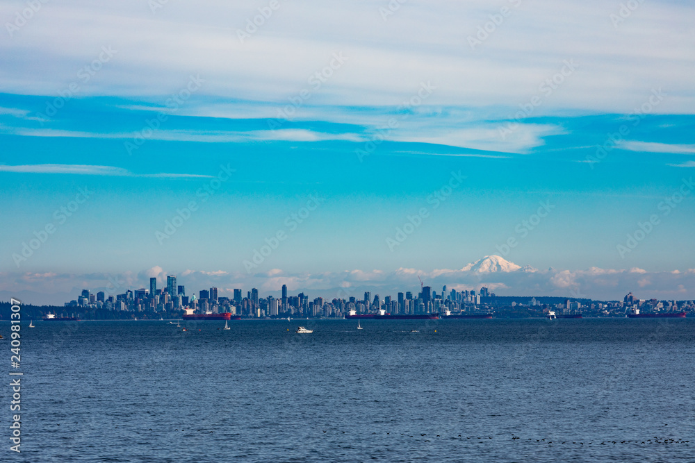 Vancouver City at the Western Canadian Pacific Ocean coast with oil tankers anchored in harbor and Mount Baker in the far distance shadowing the cityscape skyline, Biritish Columbia, BC, Canada